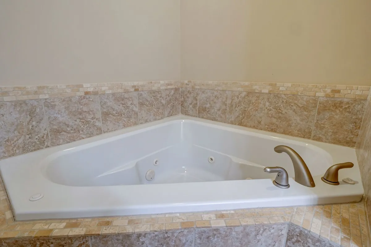 A luxurious bathroom with a jacuzzi tub surrounded by textured tiles and sleek fixtures. The mood is tranquil, with the tub inviting long, relaxing soaks and moments of self-care.