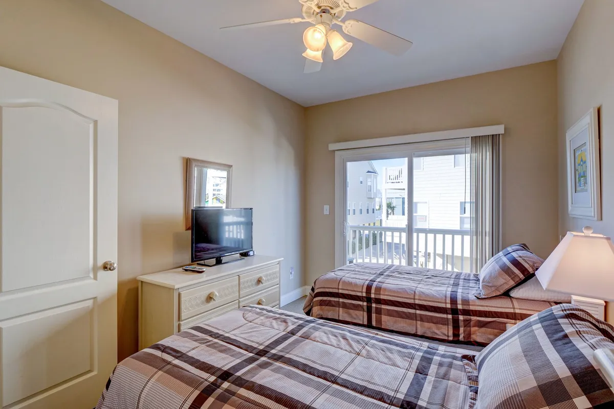 A bright and inviting twin bedroom, featuring two twin beds, a television, and a window that lets in plenty of natural light. The space is uncluttered and cheerful, ideal for kids or friends.